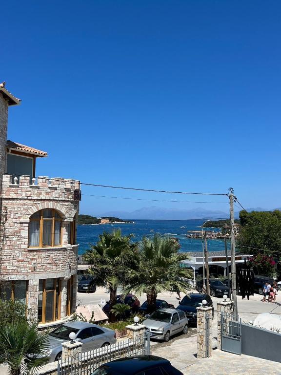 a building with cars parked in a parking lot next to the ocean at Mandi's Apartment in Ksamil