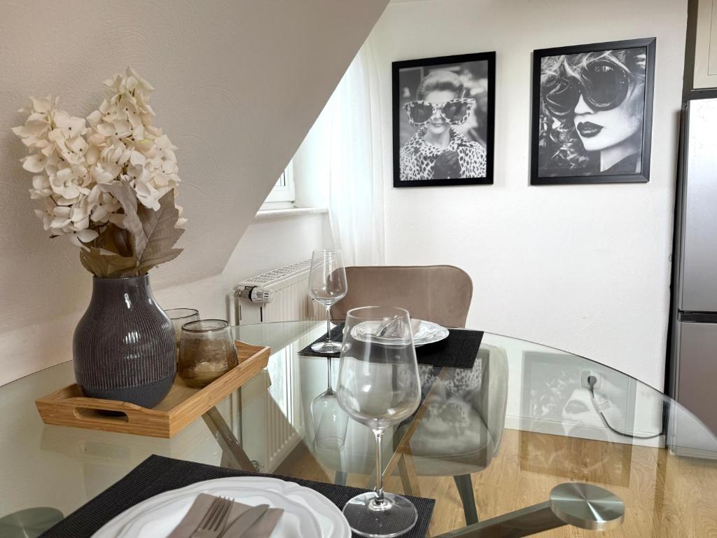 a glass table with a vase of flowers and wine glasses at Gemütliche Ferienwohnung in Ennepetal