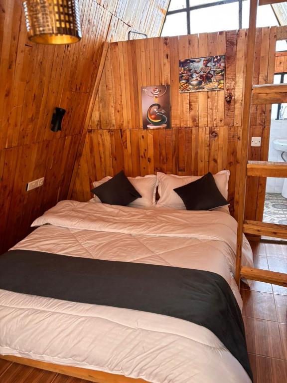 a large bed in a room with wooden walls at Kaasham Cabin Nanyuki in Nanyuki