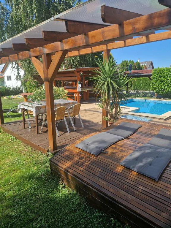 a wooden deck with a table and a swimming pool at Patrícia Panzió in Bük