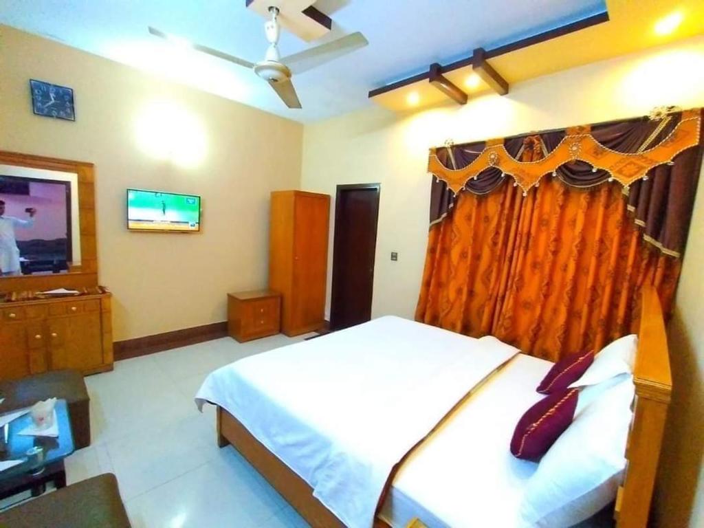 a bedroom with a bed and a television in it at Royal Residency Guest House Karachi in Karachi