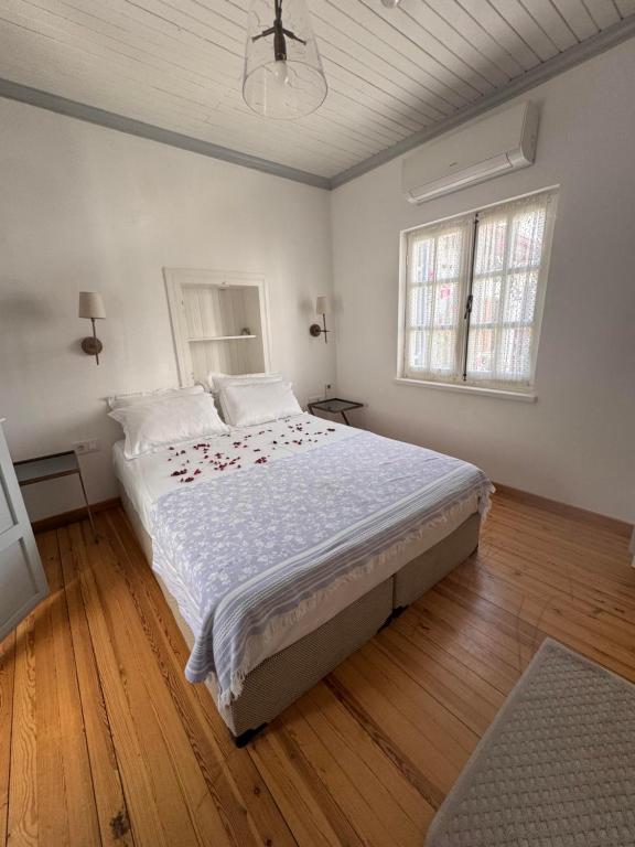 a bedroom with a large bed with white sheets and wood floors at Eden in Teos Pansiyon in Seferihisar