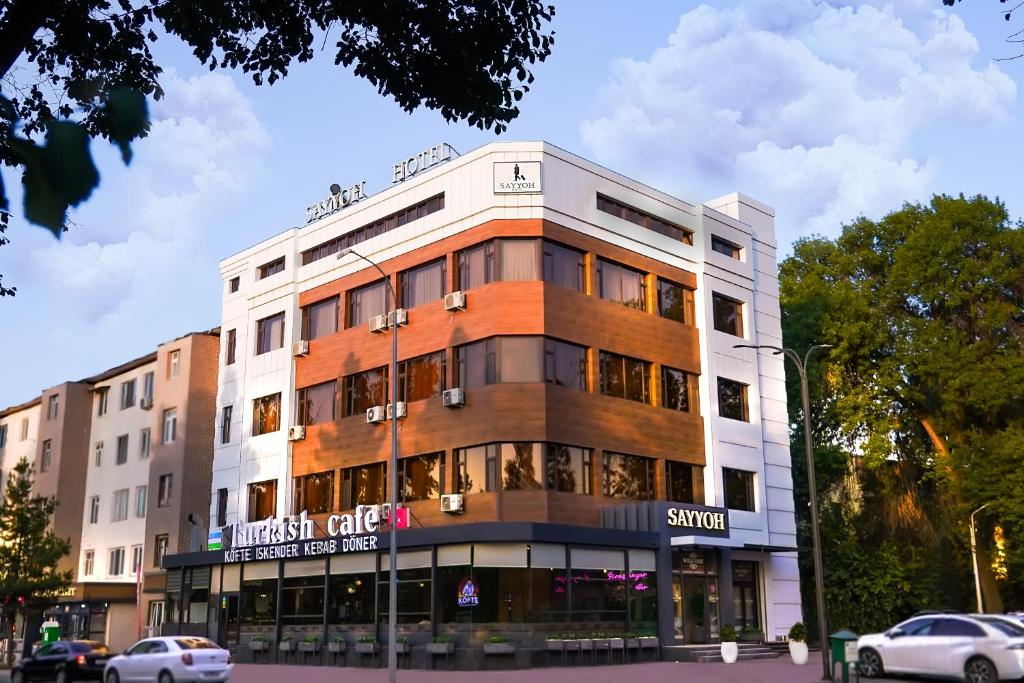 a building on a street with cars parked in front of it at Sayyoh Hotel in Tashkent