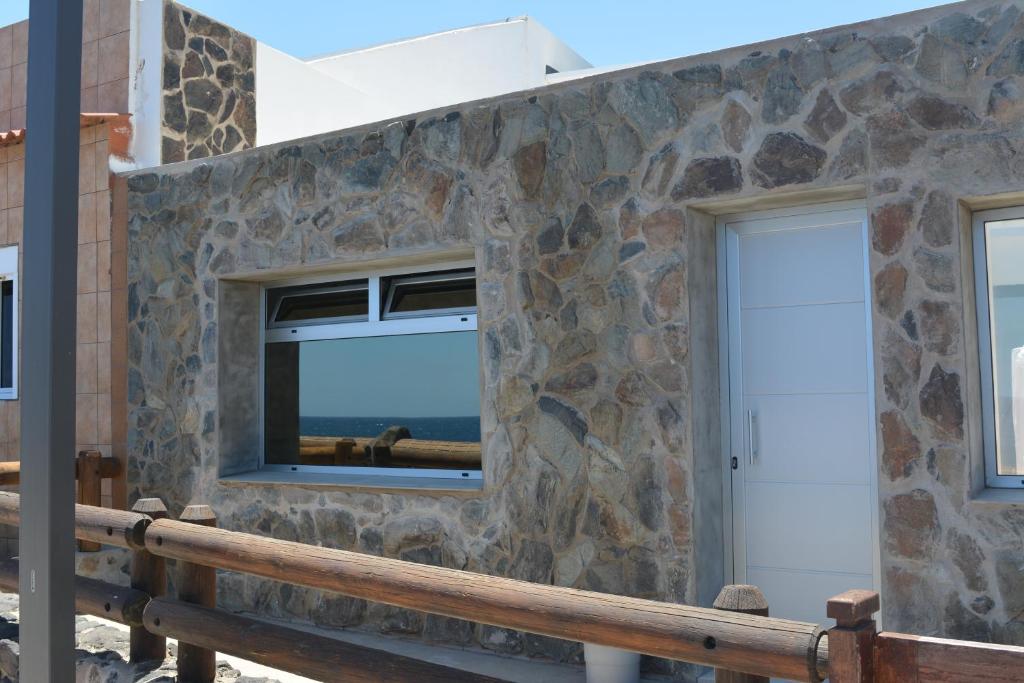 a building with two windows and a stone wall at Ian's House in La Garita