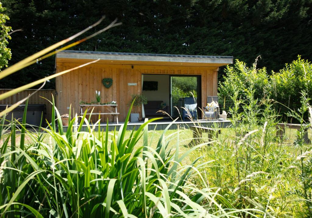 a small wooden cabin in a field of grass at Luxury Silver Birch Lodge: Hot Tub/BBQ/Fire Pit in Toppesfield
