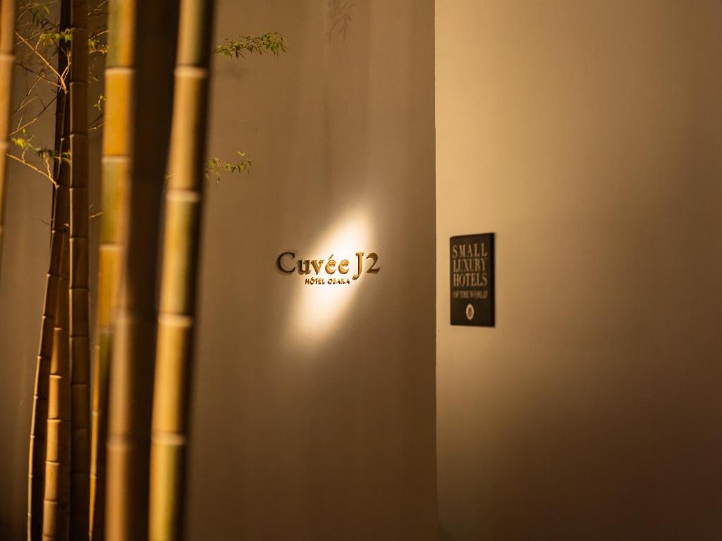 ein Schild an der Seite einer Wand mit einem Schild darauf in der Unterkunft CUVEE J2 HOTEL OSAKA by Onko Chishin in Osaka