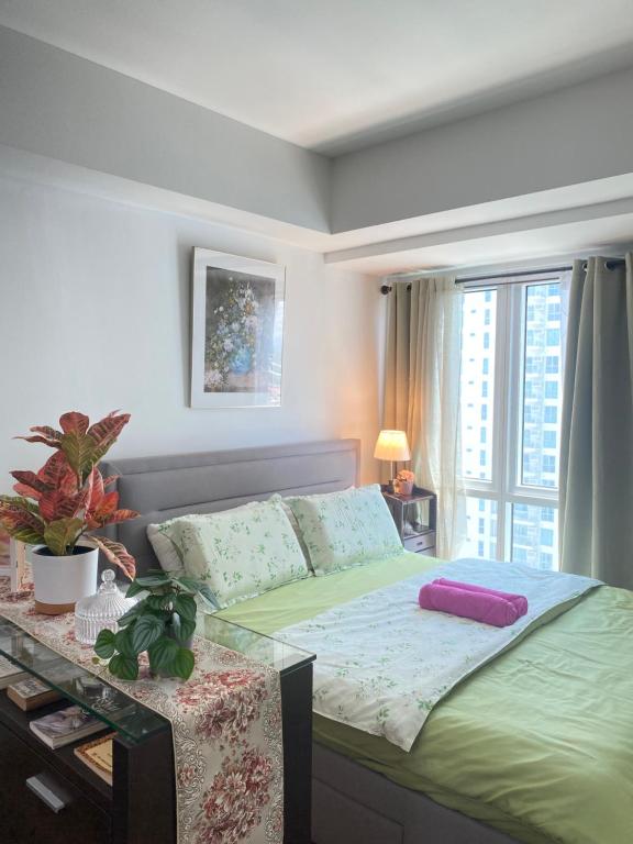 a bedroom with a green bed with a window at Midnight Cove Abreeza Place T1-1921 in Davao City