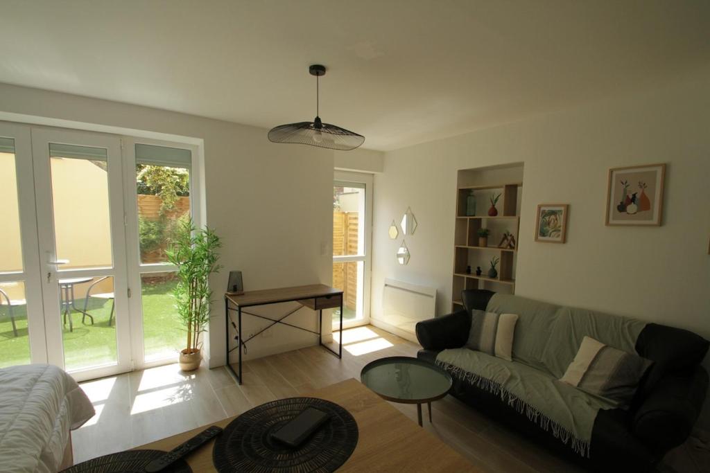 una sala de estar con un sofá y una mesa en 2-Appartement RDC 28 m2 avec Jardin, en Mantes-la-Jolie