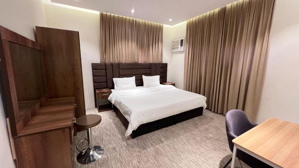 a hotel room with a bed and a desk and chair at شقق الزهور - العزيزية in AlUla