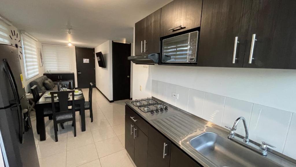 a kitchen with a sink and a table in it at Espectaculares Aptos Amoblados proximo al Parque del Cafe in Montenegro
