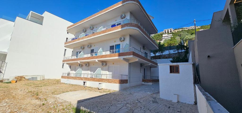 a large white building with a balcony on a hill at Sunset Hotel Roza in Vlorë