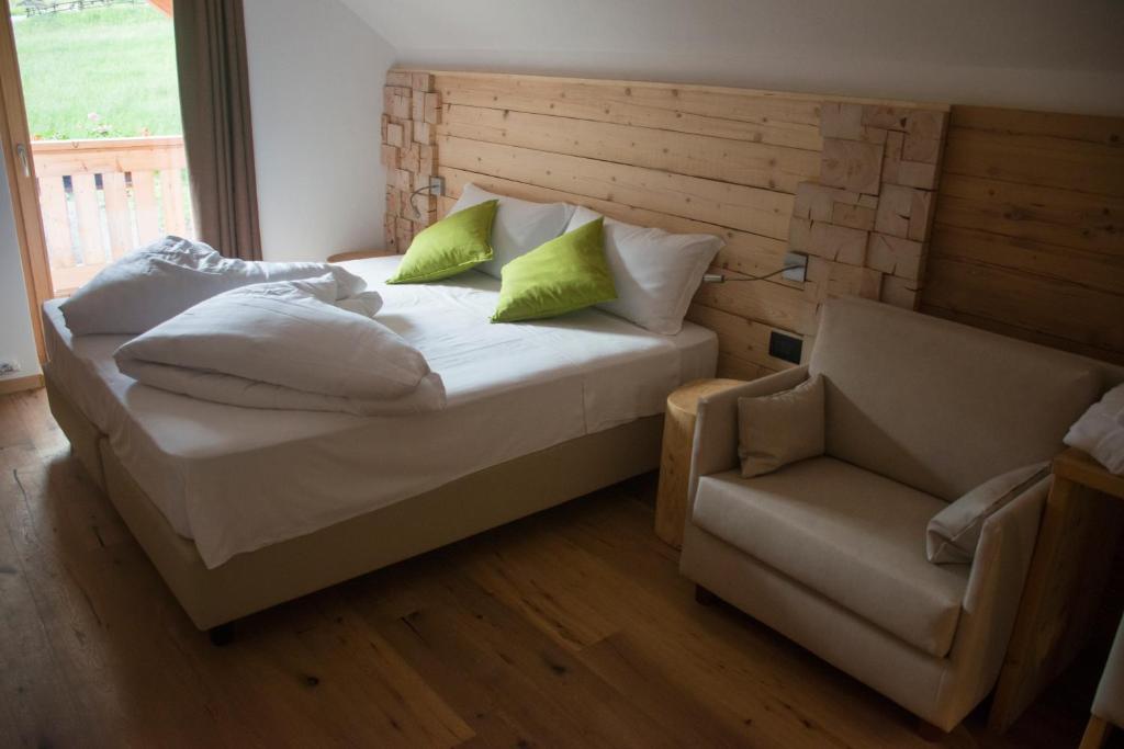 a bed with pillows and a chair in a room at Hotel Aurai in Osteria Alpina