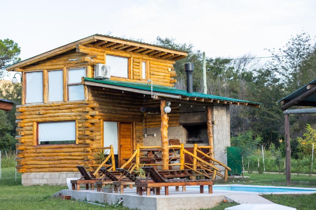 a log cabin with a deck with chairs in front at Mi lugar en el mundo in Villa Ciudad Parque