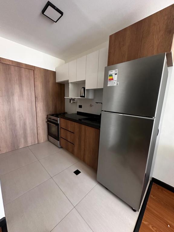 a kitchen with a stainless steel refrigerator and wooden cabinets at Exclusivo Departamento! in Cochabamba