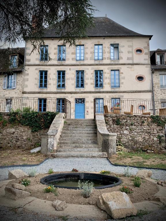 a large stone building with a staircase and a blue door at La Maison du Cèdre in Bénévent-lʼAbbaye