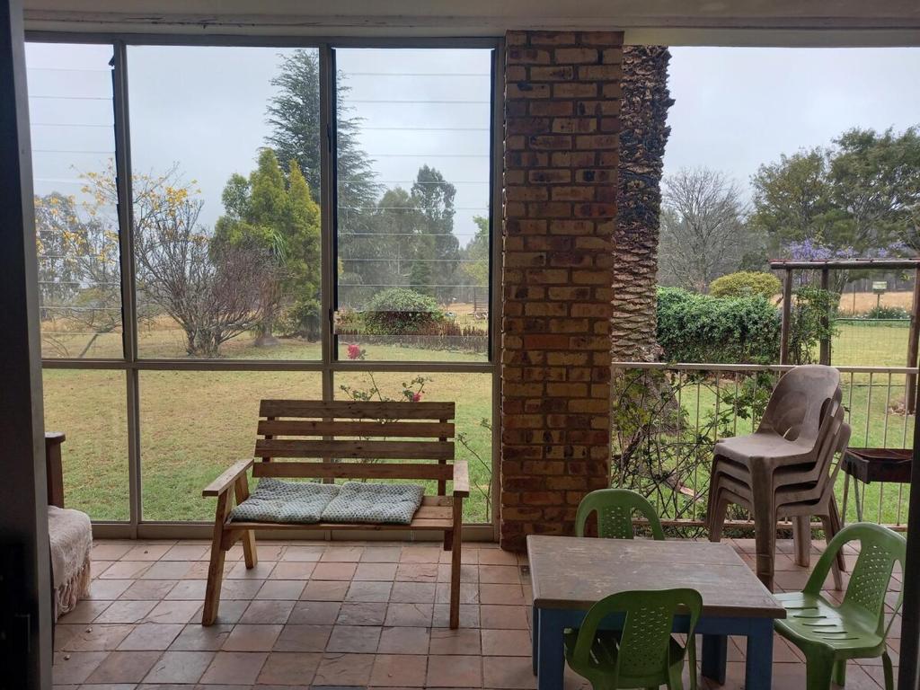 une terrasse couverte avec un banc, une table et des chaises dans l'établissement Simply Rooted Cottage, à Piet Retief