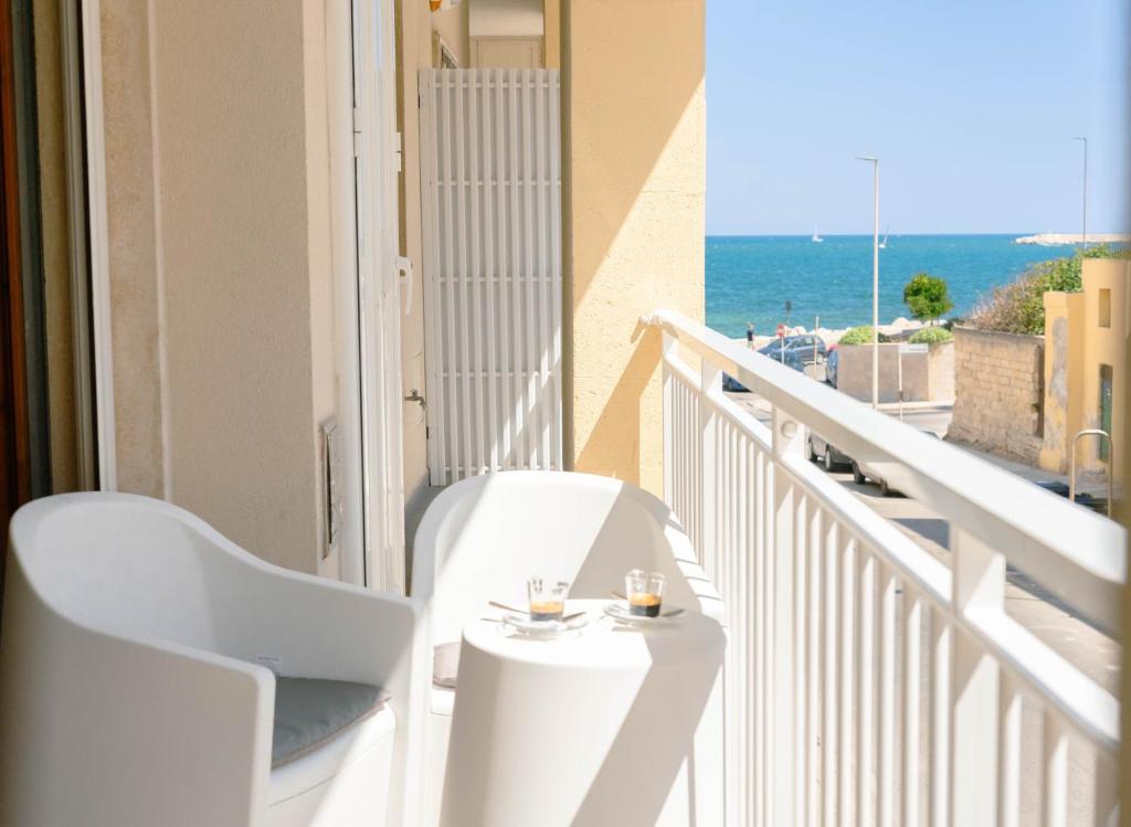 a balcony with two white chairs and a table at Levante Eight Appartamento Vista Mare in Bari