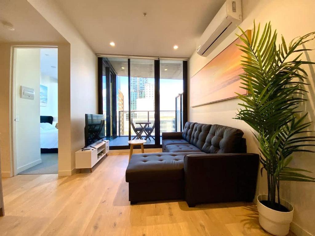 a living room with a couch and a plant at Luxury CBD Beach Vibes-Queen Bed-Gym in Adelaide