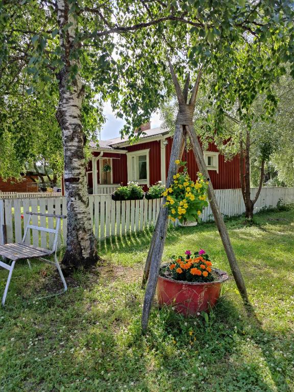 a garden swing with a basket of flowers in a yard at Koivistonpiha farmstay in Valkeakoski