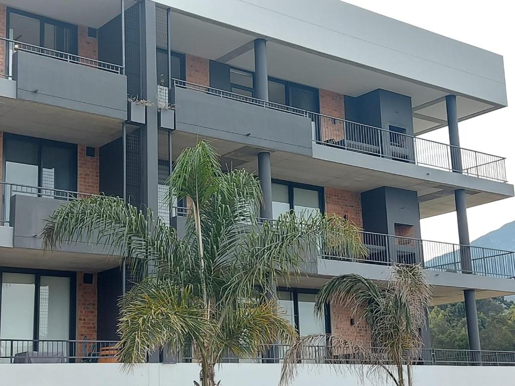 an apartment building with palm trees in front of it at 210 The Meadows in George