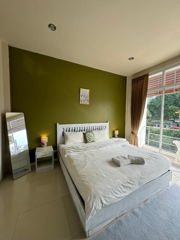 a bedroom with a large bed with a green wall at TIL DAWN Phuket in Karon Beach