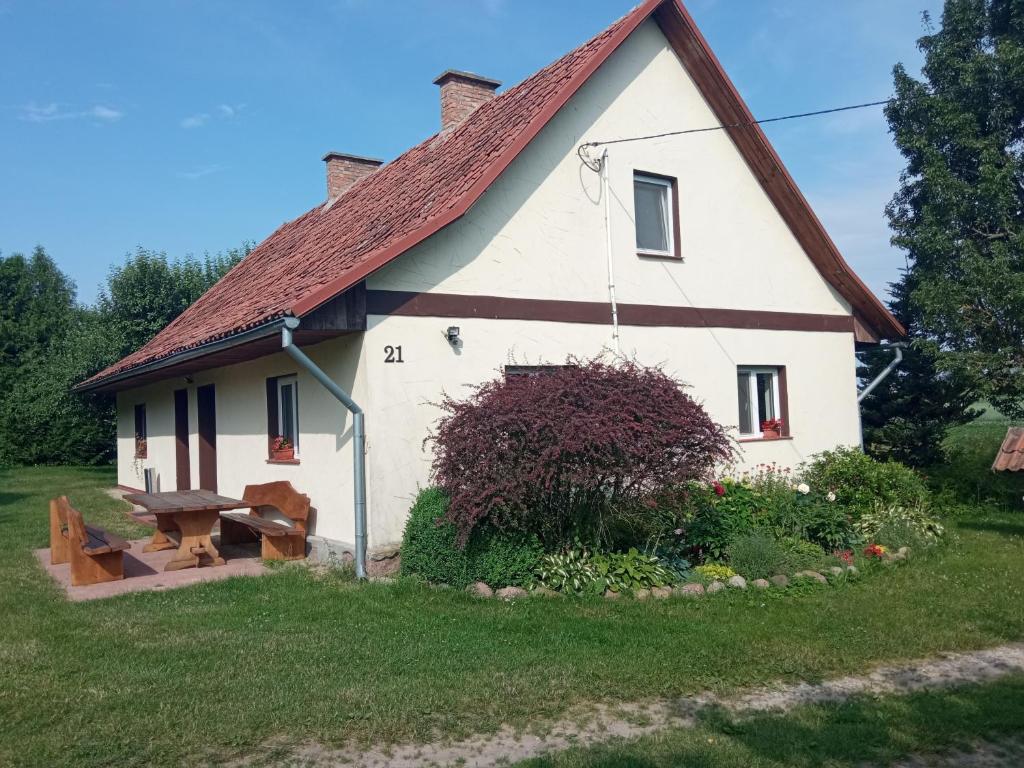 a white house with a red roof and a picnic table at domek w pobliżu jeziora in Czarnówka