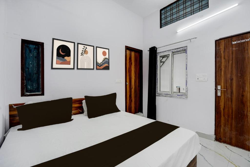 a bedroom with a white bed and some pictures on the wall at HOTEL O VIP HILL HOMESTAY in Mājra