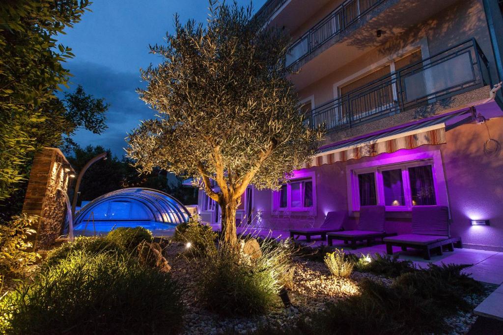 uma casa com uma árvore e luzes roxas em Anikol Apartments em Selce