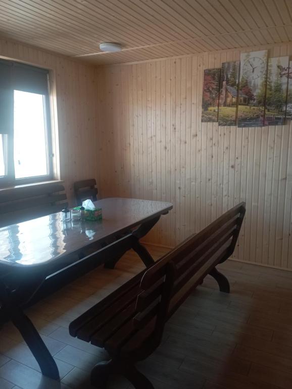 Un banco en una habitación con una mesa y una ventana. en Озеро Надії, en Ozeryany