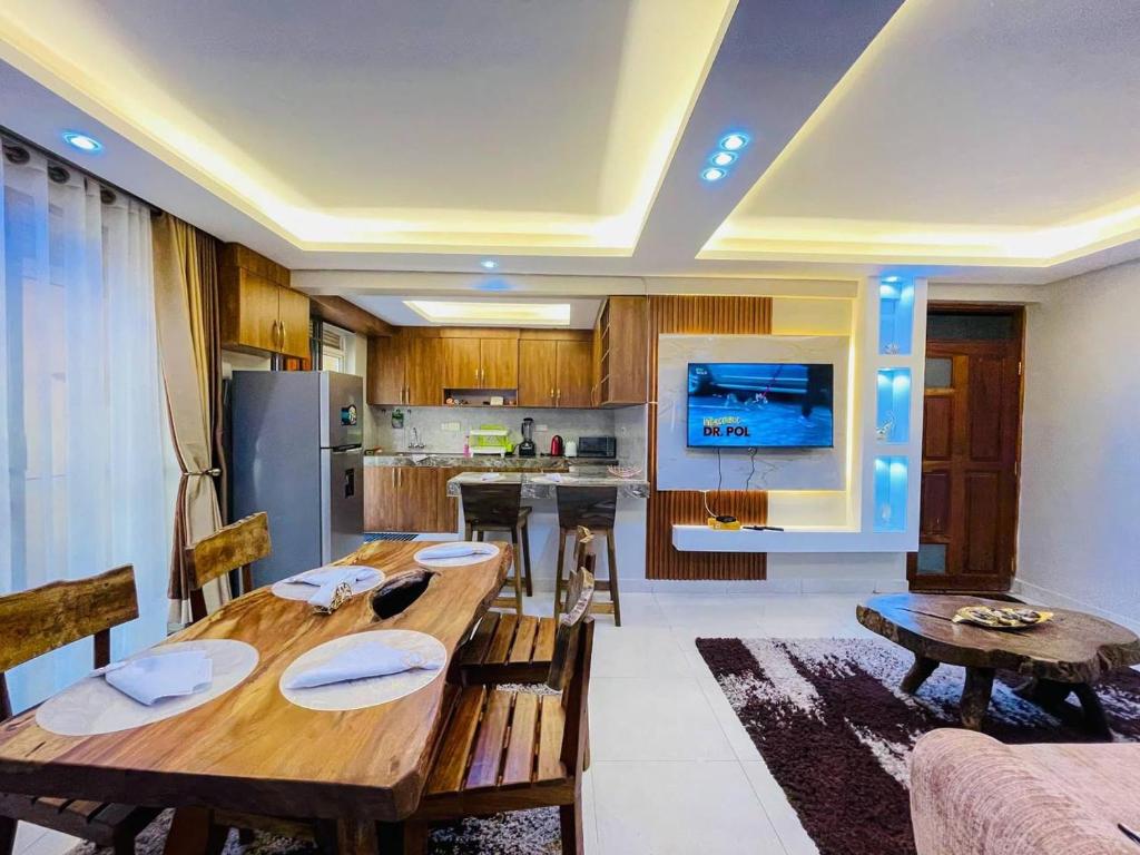 a living room with a wooden table and a kitchen at Luxurious Cozy Apartment in Kampala