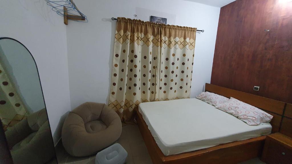 a small bedroom with a bed and a chair at Appartement meublé à Fidjrossè Cotonou in Cotonou