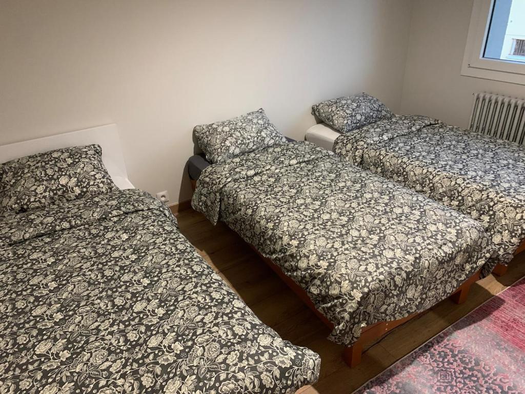 a room with three beds in a room at Petit appartement dans une maison au calme in Bonneville