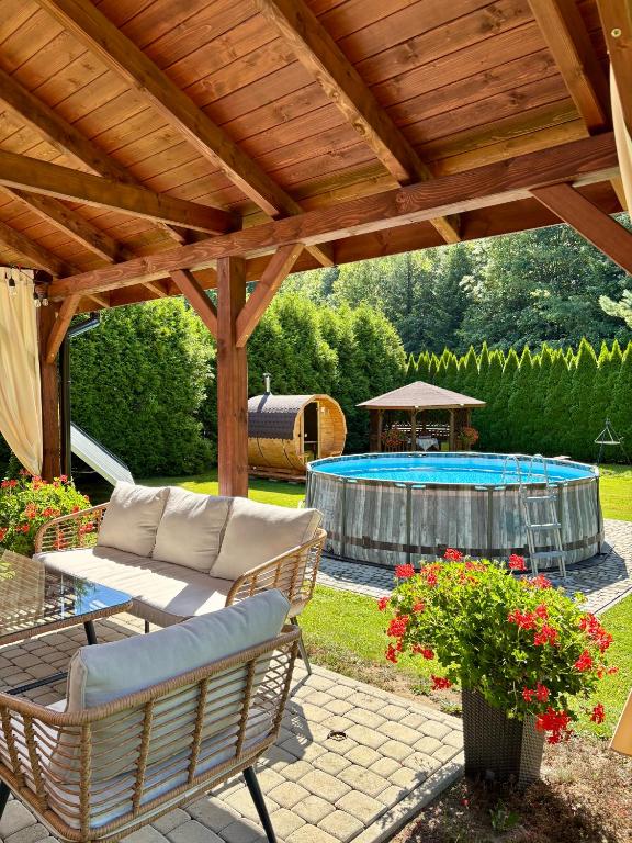 a patio with a wooden pergola and a table and chairs at Tabakowa Chata in Zawoja