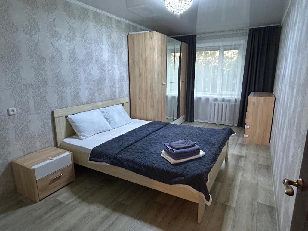 a bedroom with a bed with a blue comforter at УЮТ 2-комнатная квартира в центре in Petropavlovsk