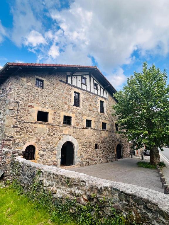 an old stone building with a tree in front of it at Goikitxe Etxea in Goizueta