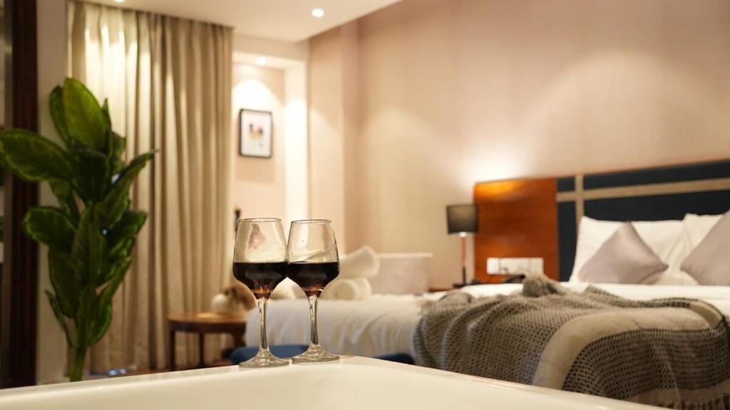 two glasses of wine sitting on a tub in a hotel room at Boutique Stay w Private Jacuzzi - Belmore Stays in Gurgaon