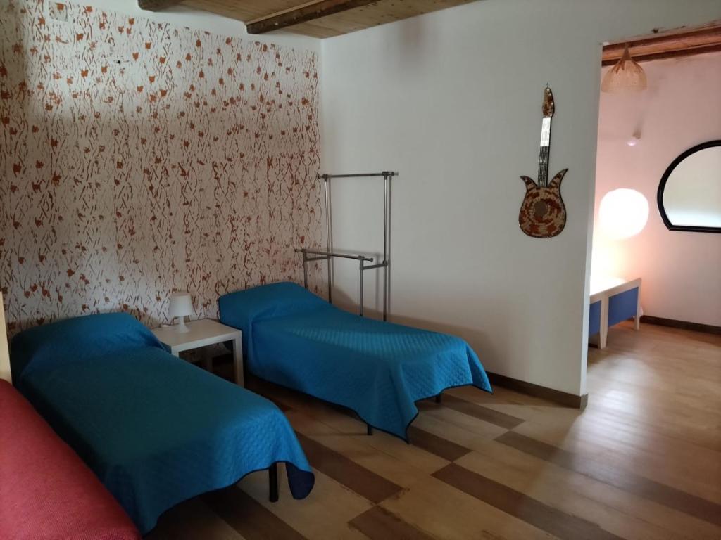 ein Zimmer mit zwei Betten und einer Gitarre an der Wand in der Unterkunft Mari e Suli in Favara