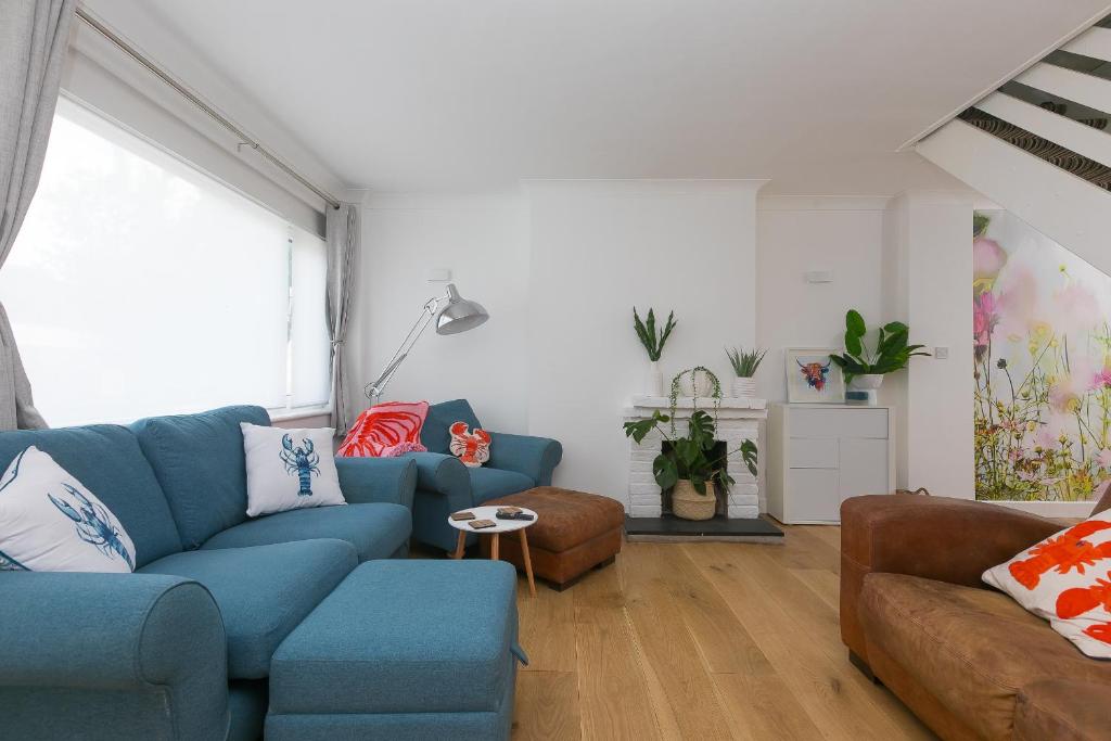 a living room with a blue couch and chairs at Pebble in Carbis Bay