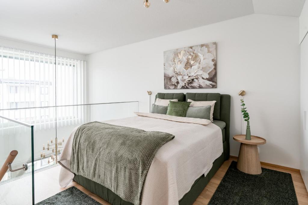 ein weißes Schlafzimmer mit einem großen Bett und grünen Kissen in der Unterkunft Loft Stadium City in Tampere