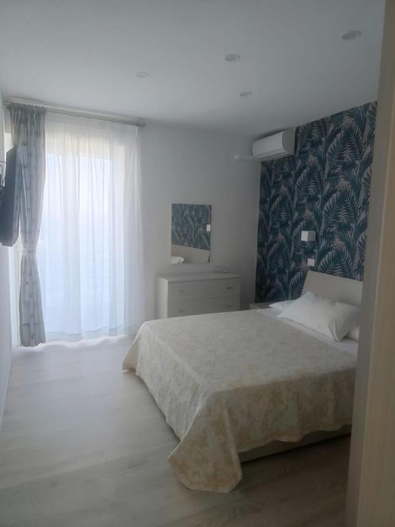 a white bedroom with a bed and a window at Maison Martina in Giardini Naxos