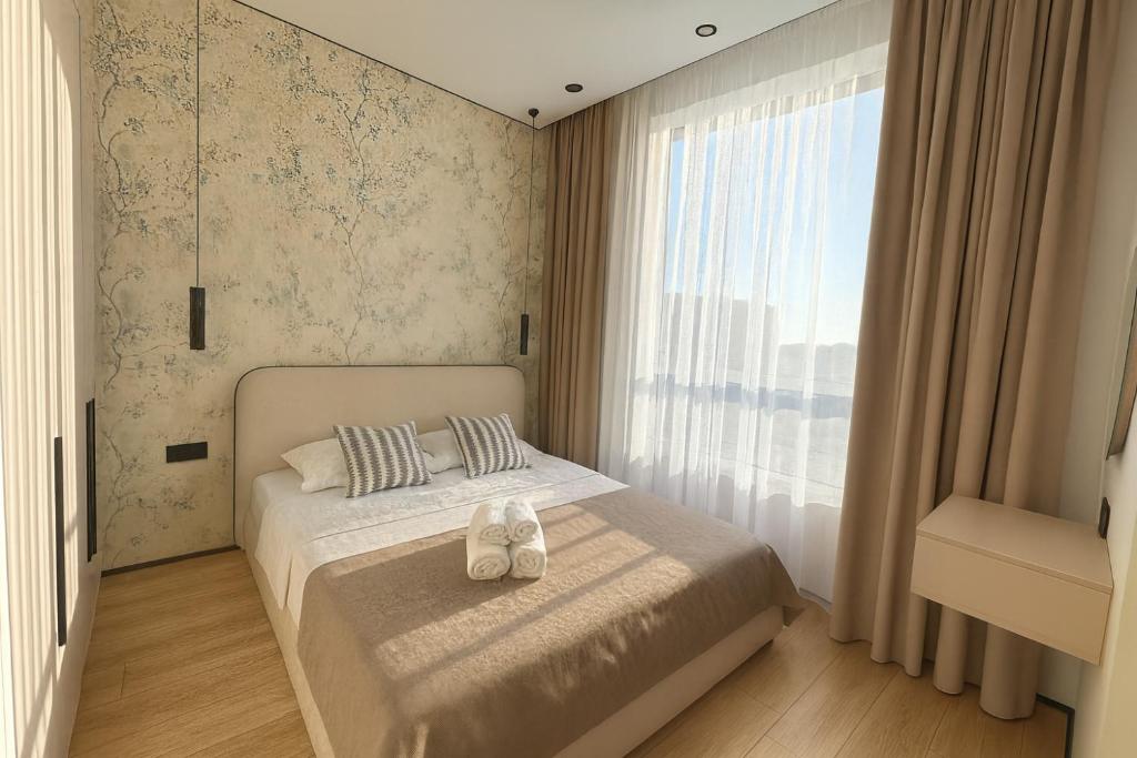 a bedroom with a bed and a large window at Уютная квартира в ЖК Республика in Astana