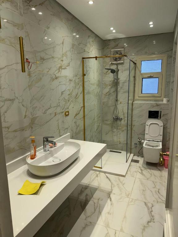 a white bathroom with a sink and a shower at Comfyheliopolis in Cairo