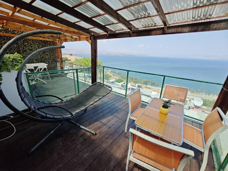 a balcony with a hammock and a table and chairs at קסם הכנרת in Tiberias