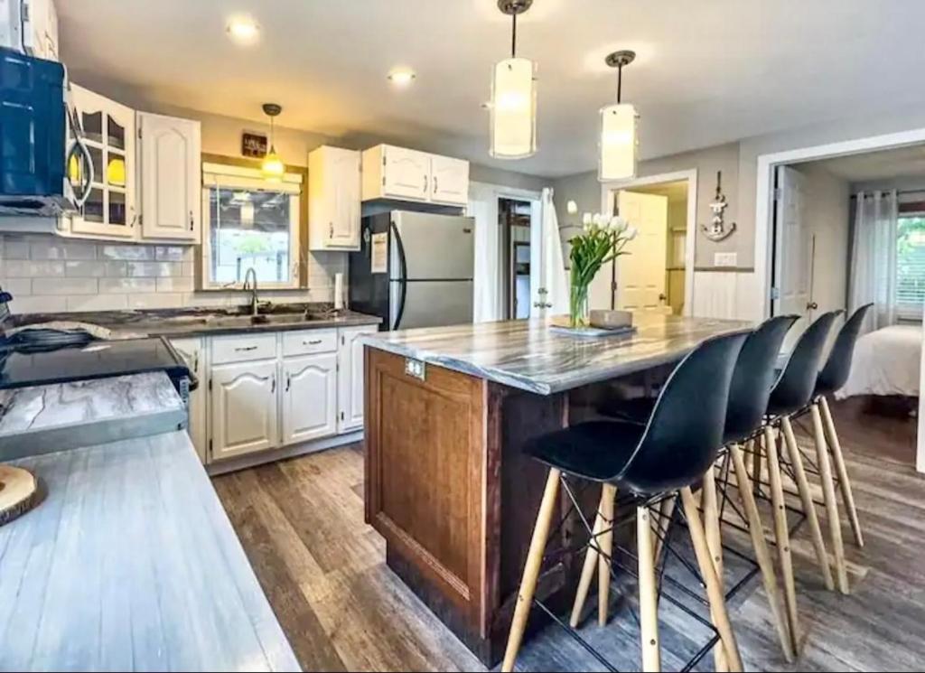 a kitchen with white cabinets and a large island with bar stools at Cozy cottage by the beach in Pointe-du-Chêne