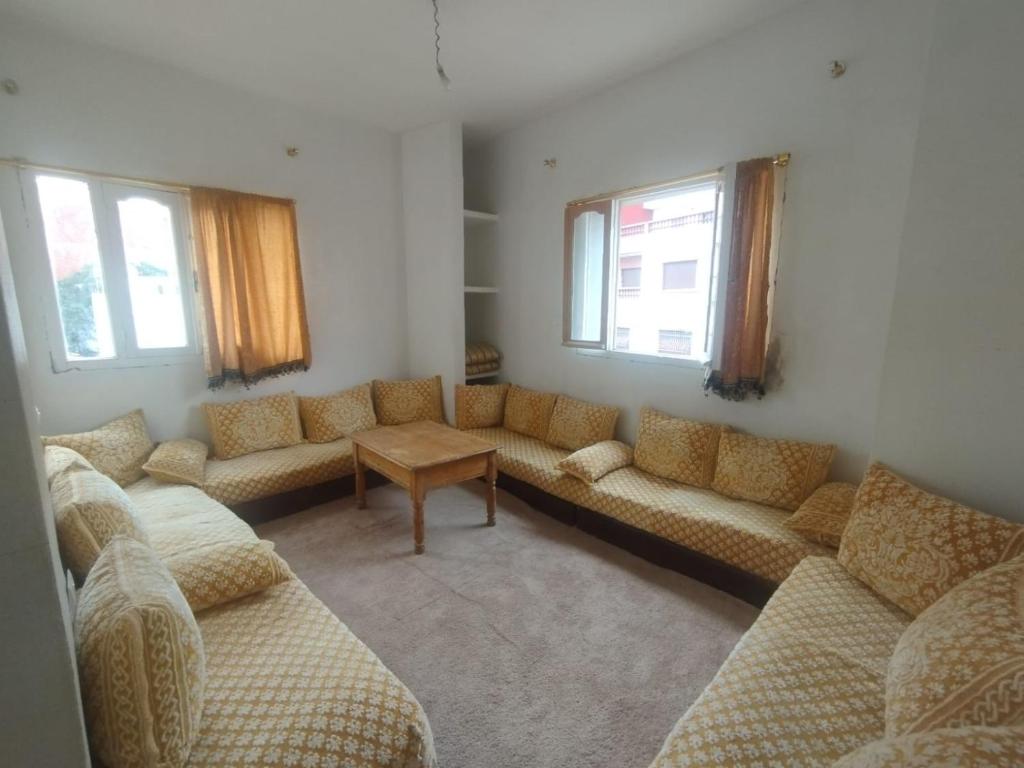 a living room with couches and a table and windows at Rabia House in Asilah