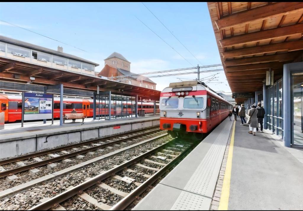 a red train is pulling into a train station at Villa Sandvika House in Kalvøya