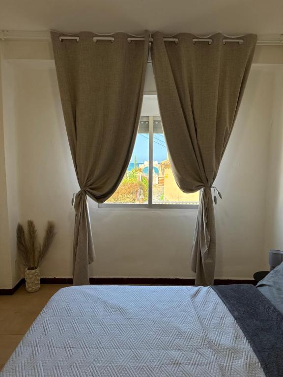 a bedroom with a window with curtains and a bed at La casa de la Brisa in Piles