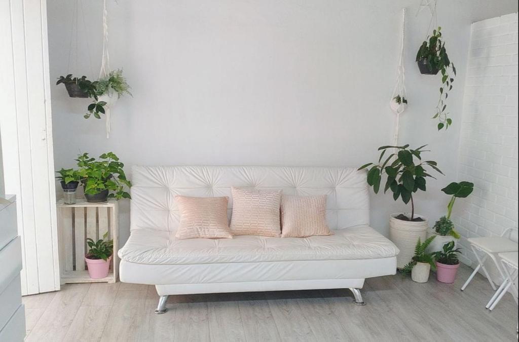 un divano bianco con cuscini rosa in una stanza con piante in vaso di Casa das Plantas a Piraju