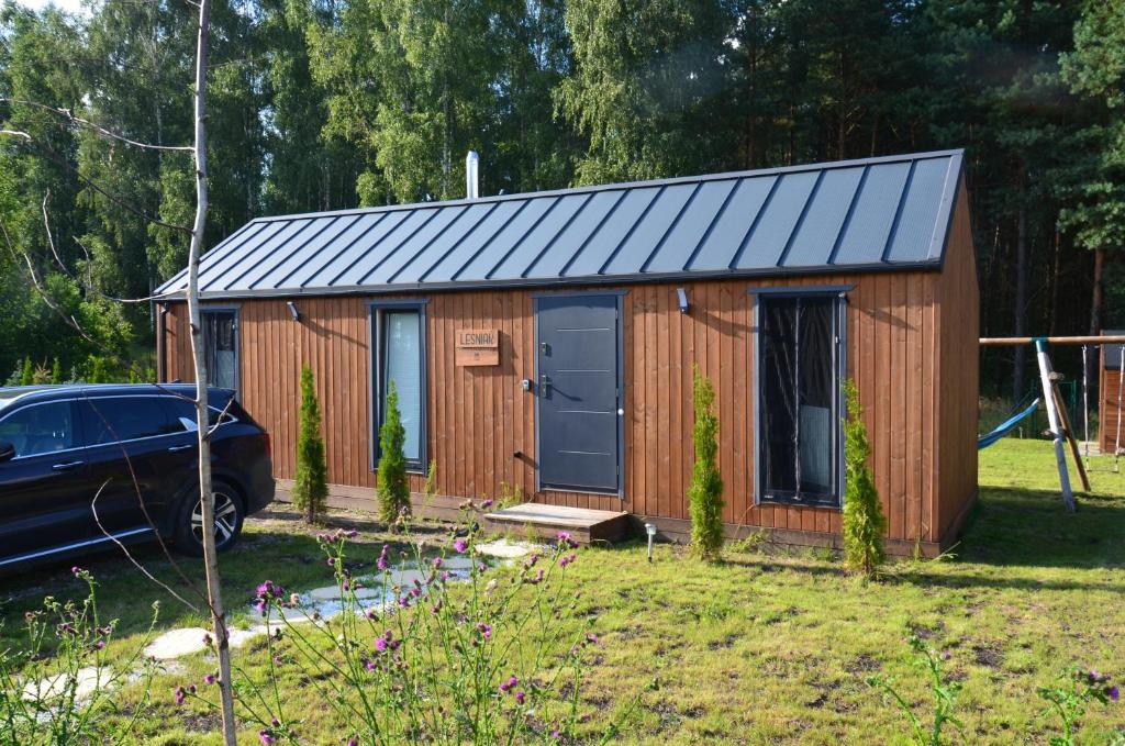 a wooden shed with a blue door in a yard at Ostoja Wycinki domki letniskowe in Jaszczerz