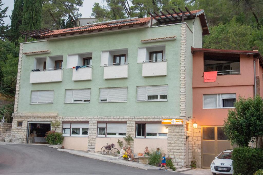 a green building with white windows and a street at Pansion 8 ferala in Novigrad Dalmatia